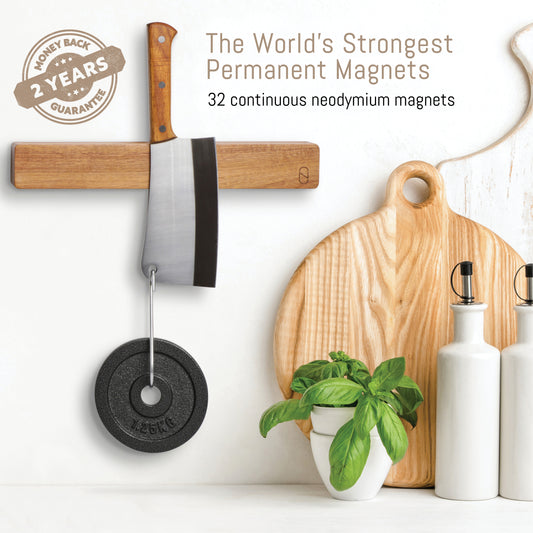 Kitchen scene with a magnet holding a knife, cutting board, and other items on a white wall.